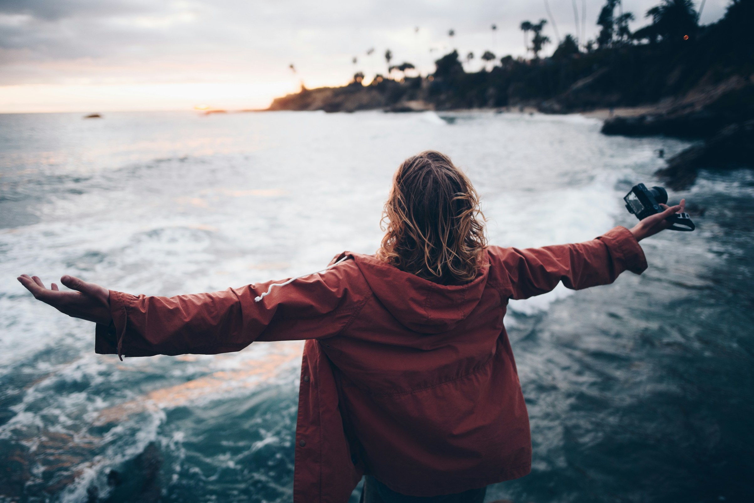 Woman with arms outstretched in front of the sea.