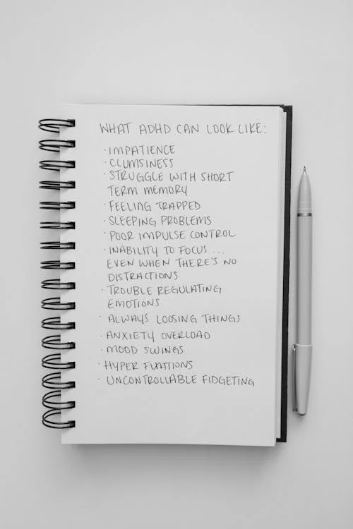 ADHD vs. Nervous System Dysregulation: Identifying the Differences. This is a list written on paper of what ADHD can look like. It includes "impatience", "struggle with short term memory", and "trouble regulating emotions".